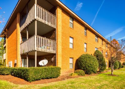 Exterior view of an apartment building surrounded by a well-maintained lawn and decorative bushes.