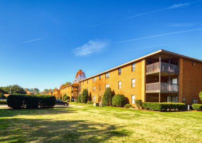 A modern apartment complex situated at the edge of a lush green lawn, showcasing a vibrant and inviting outdoor space.