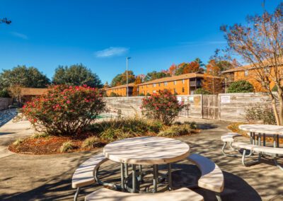 Outdoor courtyard with picnic tables and benches, designed for socializing and leisure among apartment residents.